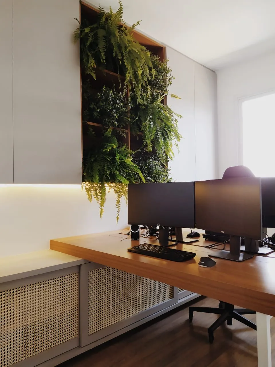 Home office com painel verde e mesa em madeira